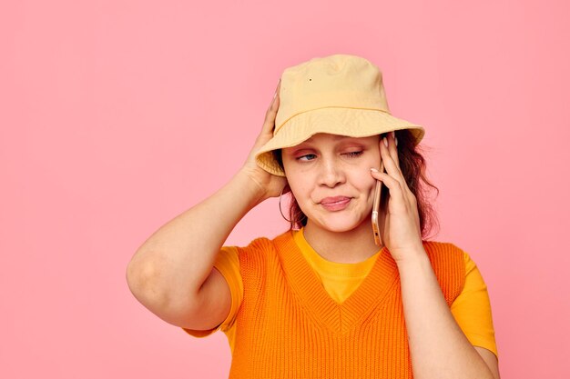 Jolie femme communique au téléphone sur fond rose mode chapeau jaune inchangé