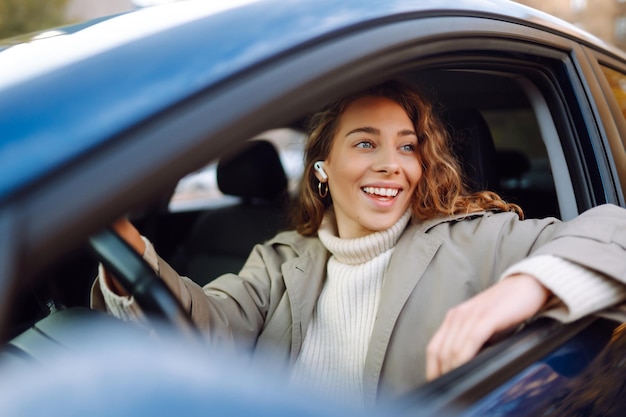 Photo une jolie femme conductrice vous sourit de la voiture concept de style de vie automobile journey partage de voiture