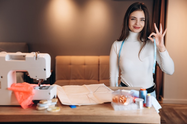 Jolie femme couturière à lunettes coud des vêtements sur machine à coudre