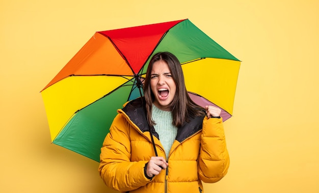 Jolie femme criant agressivement avec une expression de colère. concept d'hiver et de parapluie