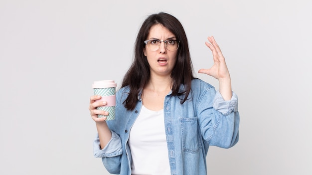 Jolie femme criant avec les mains en l'air et tenant un café à emporter