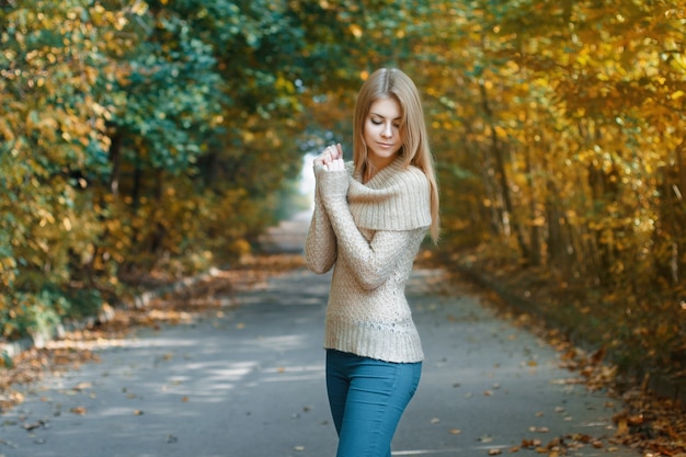 Jolie femme dans un maillot debout dans le parc de l'automne