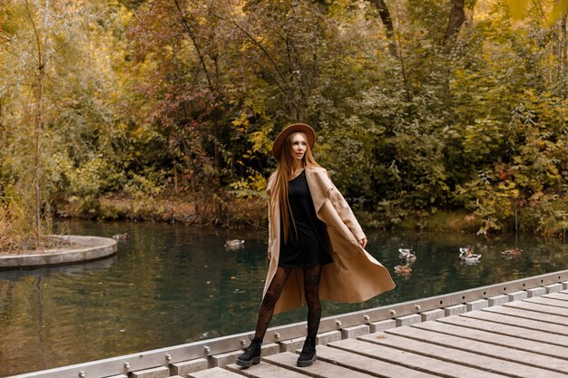 Une jolie femme dans un manteau d'automne dans un parc de la ville. humeur d'automne