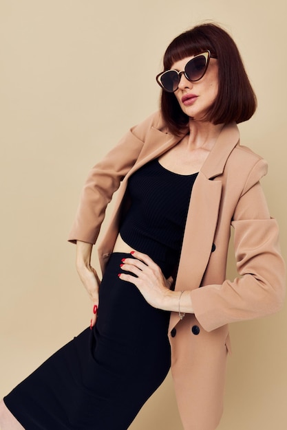 Jolie femme dans une veste beige lunettes de soleil de style élégant fond isolé