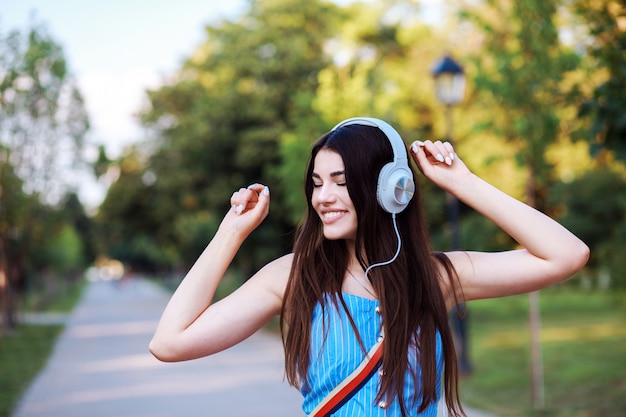 Jolie femme danse tout en écoutant de la musique en plein air.