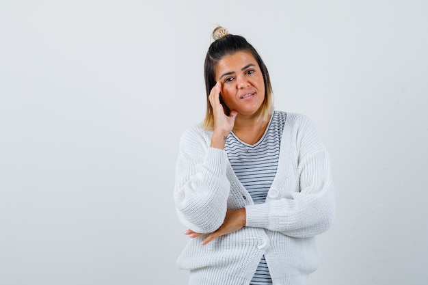 Jolie femme debout en pensant pose en t-shirt, cardigan et semblant raisonnable.