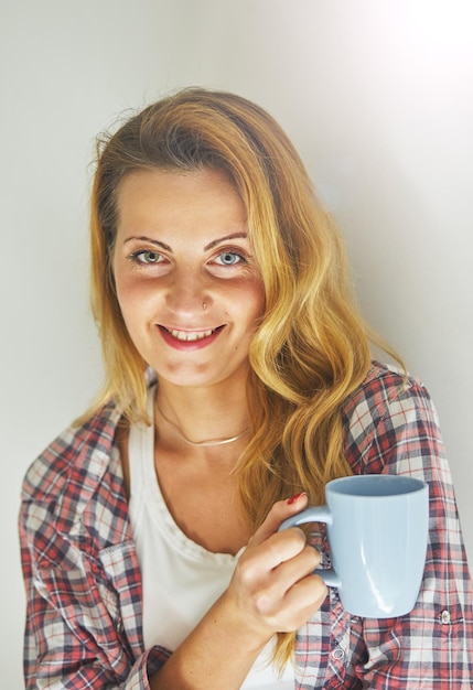 Jolie femme debout, tenant une tasse de café