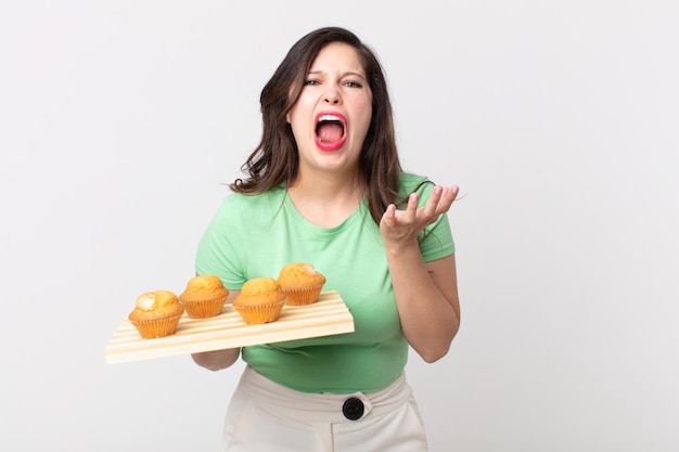 Jolie femme à la désespérée, frustrée et stressée et tenant un plateau de muffins