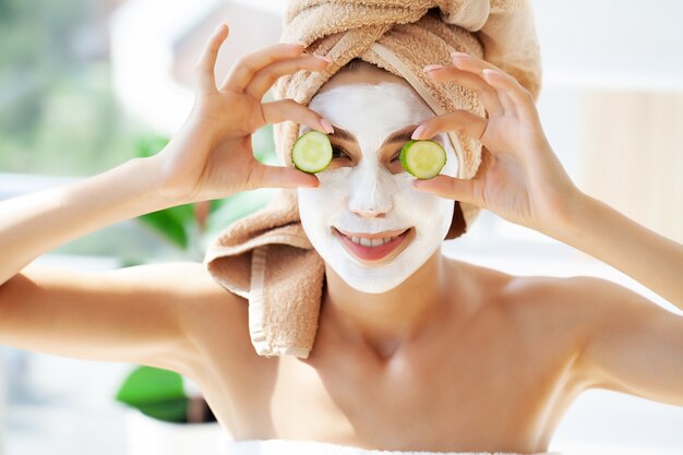 Jolie femme drôle avec un masque d'argile sur son visage.