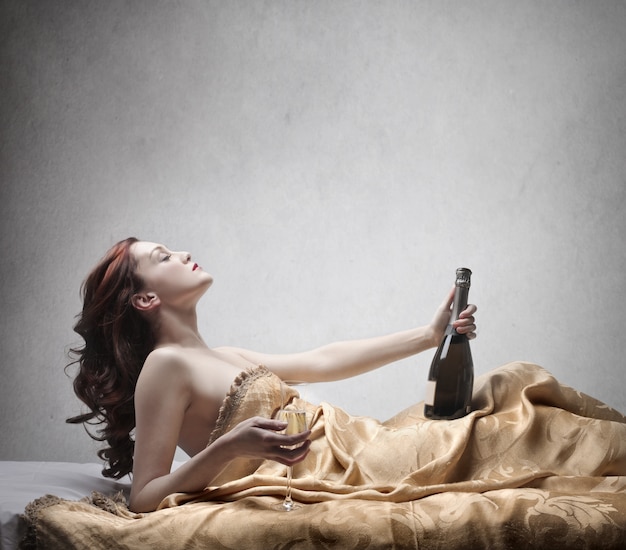 Jolie femme avec du champagne au lit