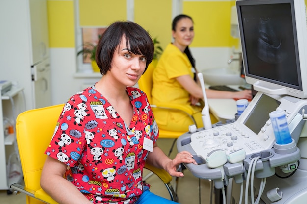 Jolie femme échographiste travaillant à l'équipement à ultrasons