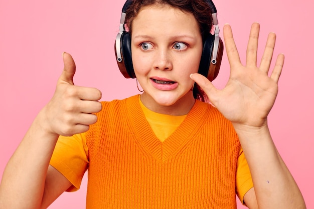 Jolie femme écoutant de la musique avec un casque chandail orange émotions fun vue recadrée inchangée