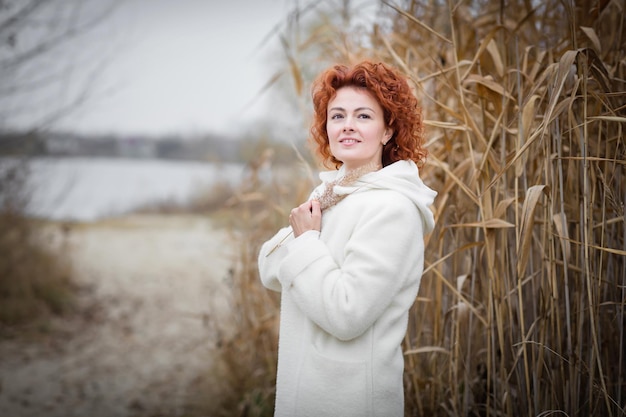 Jolie femme élégante tenant un roseau sec marchant dans le parc