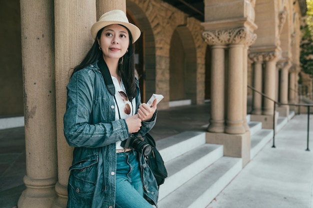 jolie femme élégante tenant son guide et visitant un nouvel endroit très joyeusement.