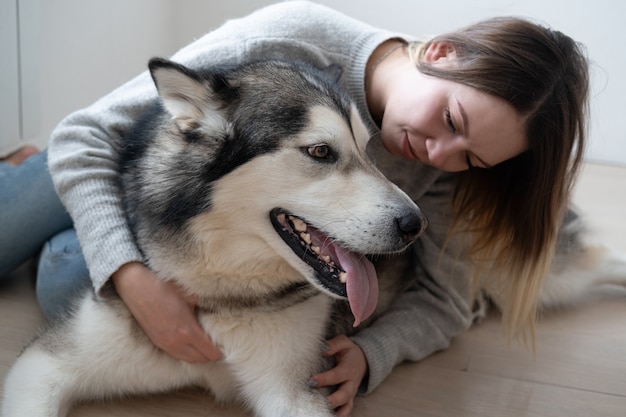 Jolie femme embrassant le chien malamute d'Alaska sur le sol.