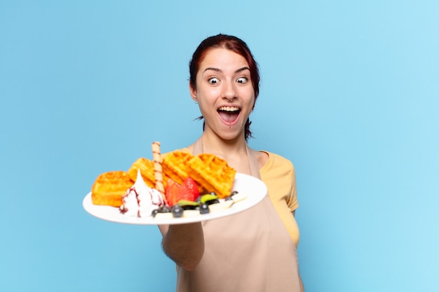 Jolie femme employée de boulangerie avec des gaufres et des gâteaux