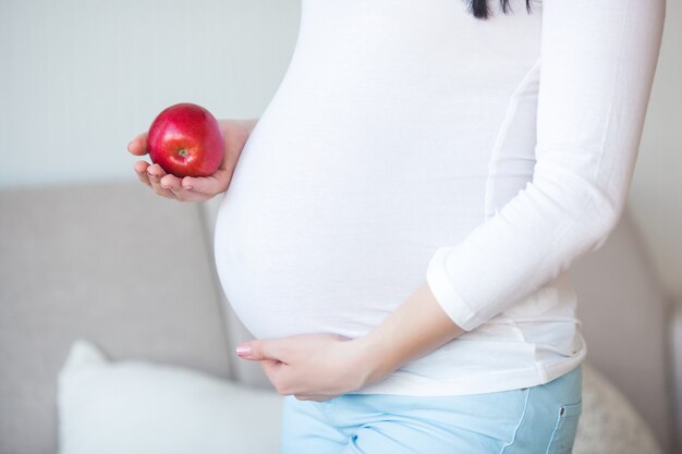 Jolie femme enceinte avec apple. Attend femme tenant des aliments sains. Dame mangeant une pomme rouge. Une bonne nutrition pour la grossesse.