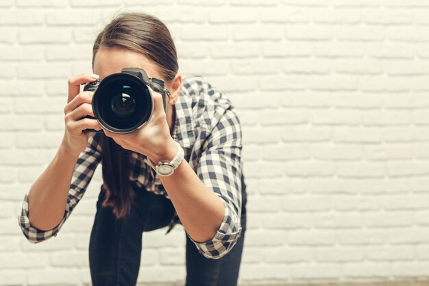 Jolie femme est un photographe professionnel avec appareil photo reflex numérique