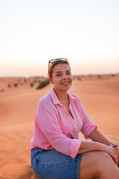 Jolie femme européenne assise sur la crête d'une dune dans le désert