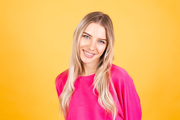 Jolie femme européenne en chemisier rose sur mur jaune