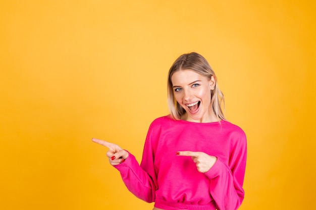 Jolie femme européenne en chemisier rose sur mur jaune