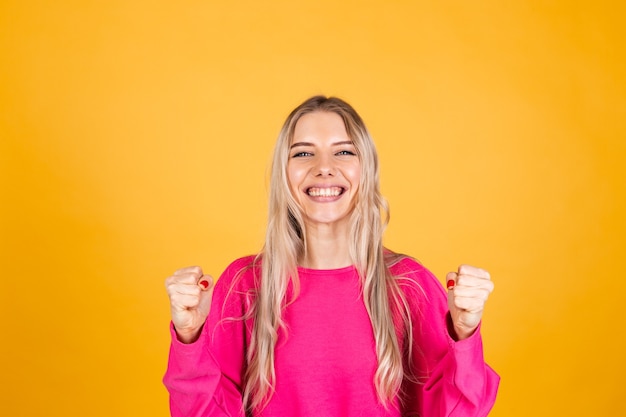 Jolie femme européenne en chemisier rose sur mur jaune