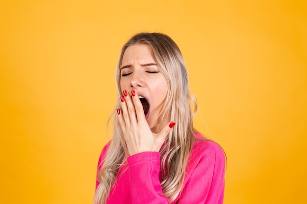 Jolie femme européenne en chemisier rose sur mur jaune