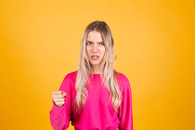 Jolie femme européenne en chemisier rose sur mur jaune