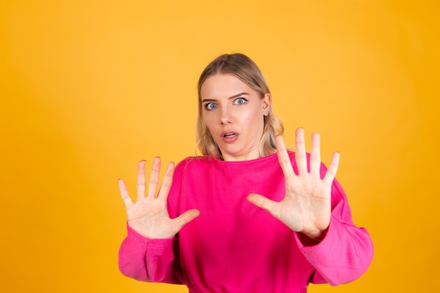 Jolie femme européenne en chemisier rose sur mur jaune