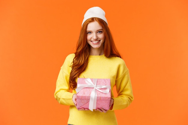 Jolie femme européenne rousse prépare un cadeau, un cadeau emballé et le donne pendant les vacances de Noël