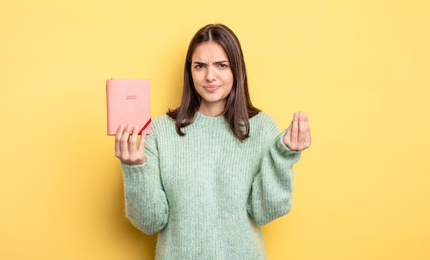 Jolie femme faisant un capice ou un geste d'argent, vous disant de payer. notion de planificateur