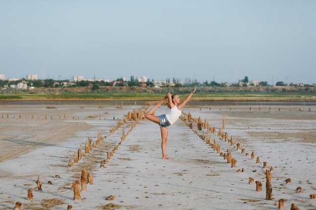 La jolie femme faisant du yoga sur le terrain à l'extérieur