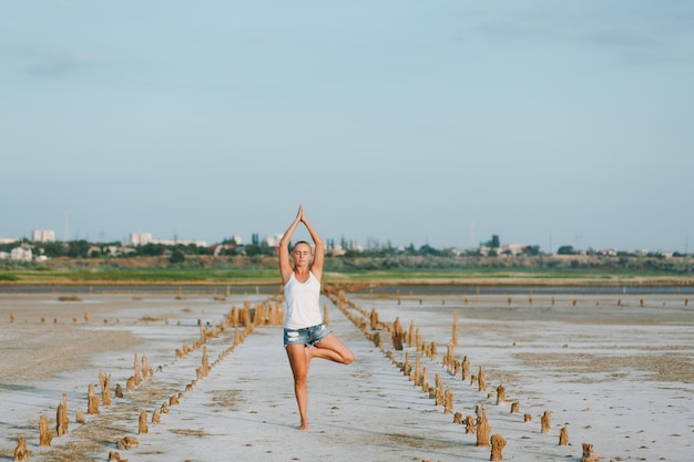 La jolie femme faisant du yoga sur le terrain à l'extérieur