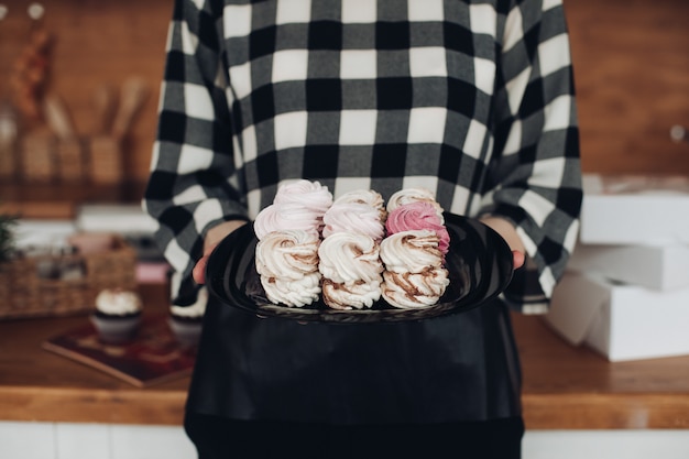 Jolie femme a fait des guimauves, les mettre dans une boîte et le montre dans sa grande cuisine lumineuse