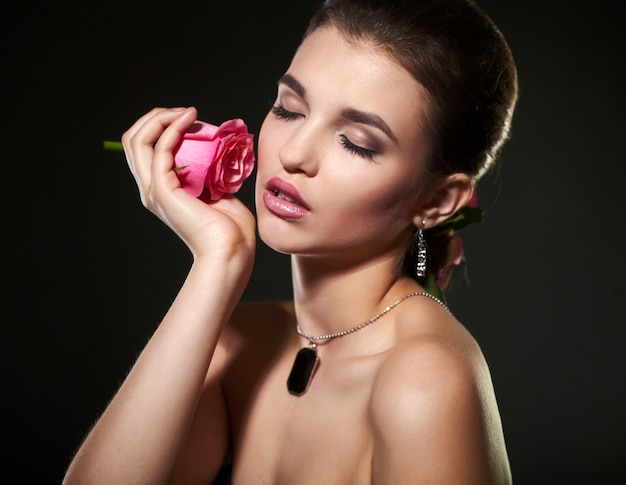 Jolie femme femme brune avec rose en studio