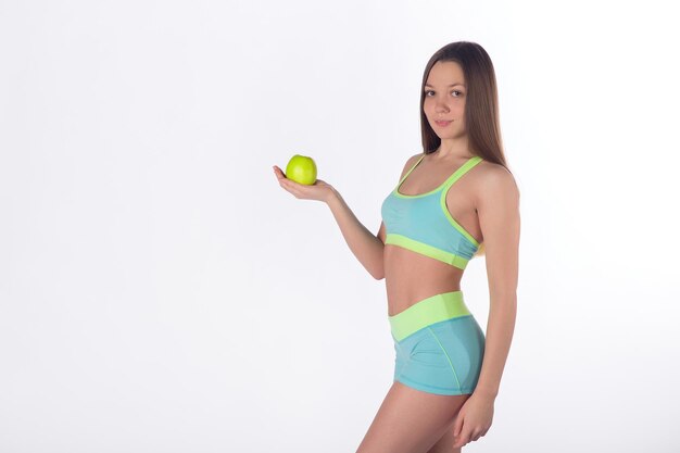 Jolie femme fitness pose avec pomme, fond blanc