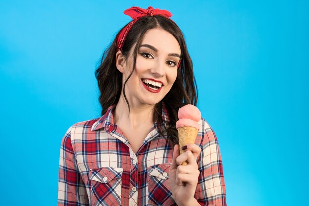 La jolie femme avec une glace sur fond bleu