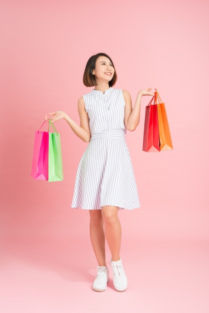 Jolie femme glamour dans une robe bleu clair sur fond rose shopping