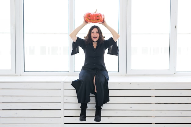 Jolie femme gothique dans des vêtements de style halloween avec citrouille dans les mains