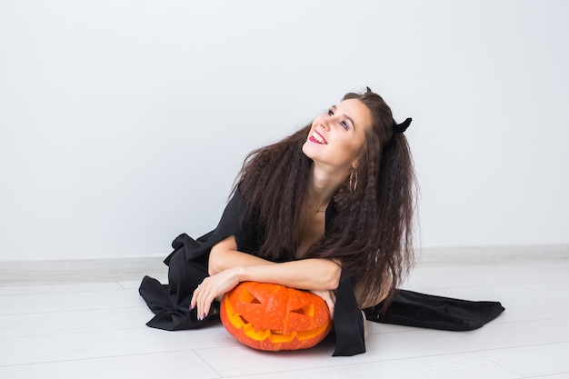 Jolie femme gothique dans des vêtements de style halloween avec citrouille dans les mains