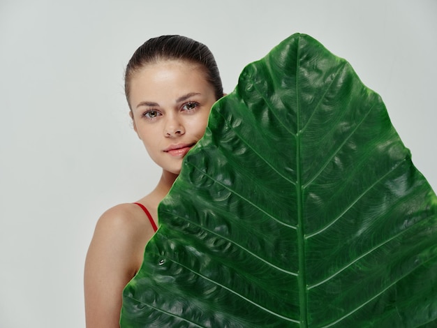 Jolie femme grande feuille verte studio vue recadrée