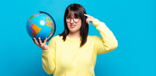 Jolie femme grande taille se sentant confuse et perplexe, montrant que vous êtes fou, fou ou fou