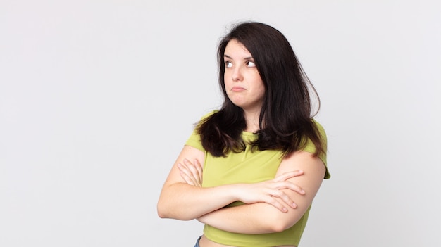 Jolie femme haussant les épaules, se sentant confuse et incertaine, doutant avec les bras croisés et le regard perplexe