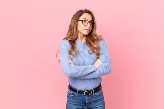 Jolie femme haussant les épaules, se sentant confuse et incertaine