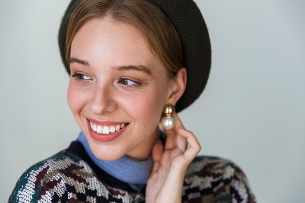 jolie femme heureuse portant des boucles d'oreilles posant et souriant isolé sur blanc