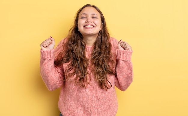 Jolie femme hispanique à l'air extrêmement heureuse et surprise, célébrant le succès, criant et sautant