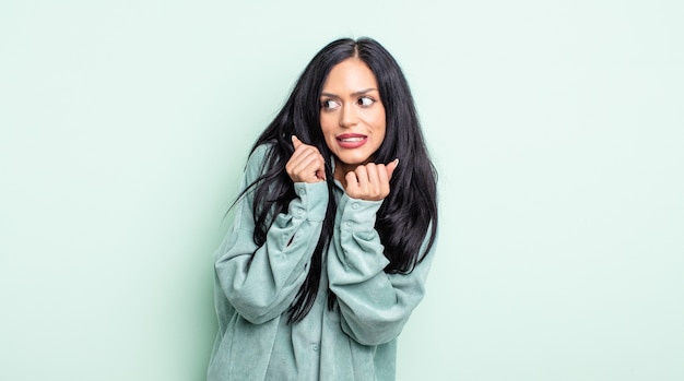 Jolie femme hispanique à l'air inquiète, anxieuse, stressée et effrayée, se rongeant les ongles et regardant vers l'espace de copie latéral