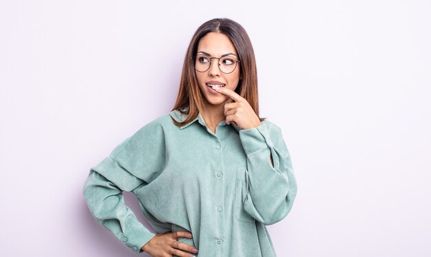 jolie femme hispanique au regard surpris, nerveux, inquiet ou effrayé, regardant de côté vers l'espace de copie