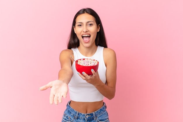 Jolie femme hispanique avec un bol de petit déjeuner avec des flocons