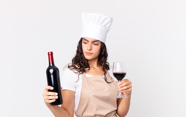 Jolie femme hispanique de chef avec une bouteille de vin